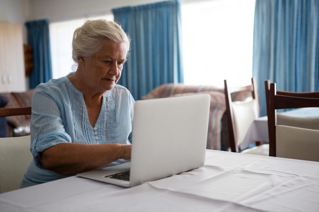Senior woman using laptop while sitting in nursing home
